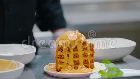 餐厅厨房在蜂蜜蛋糕的顶部倒入甜酱和麦片视频的预览图