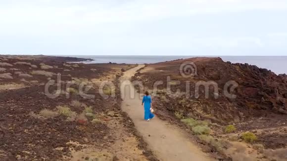 穿着漂亮的蓝色连衣裙和帽子的女性在大西洋海岸的一个保护区漫步视频的预览图