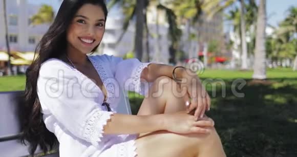 公园长椅上穿白裙子的漂亮女孩视频的预览图