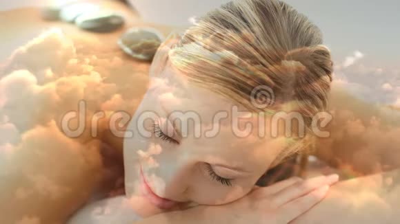 美丽的金发女人躺在温泉浴场背部放着炽热的玄武岩石为瓦伦丁的云景视频的预览图