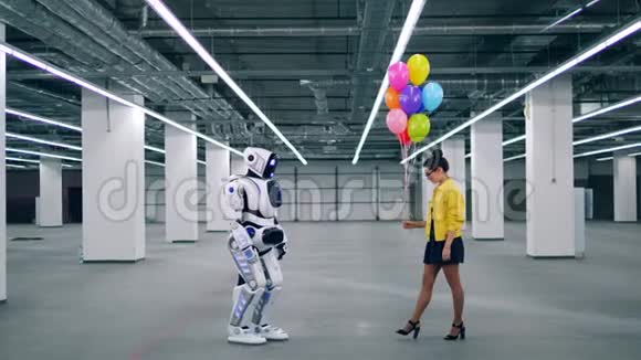 年轻的女士正在给一个像人一样的半机器人送气球视频的预览图
