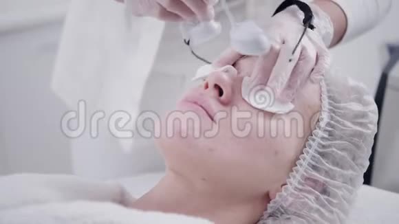 医生给病人戴上护目镜用专业设备抗痘光疗美容院的美女视频的预览图