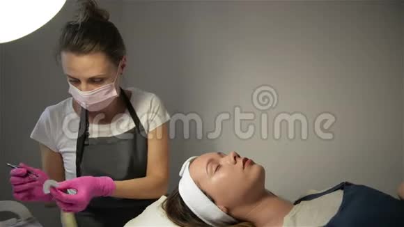 一个非常漂亮的女孩在美容沙龙做一个层压睫毛美容师执行手术睫毛视频的预览图