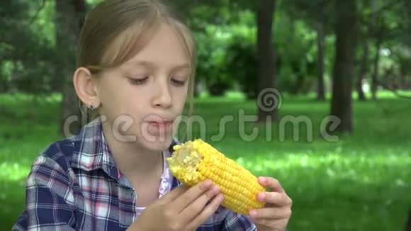 公园户外儿童吃煮玉米饥饿女孩吃健康零食4K视频的预览图