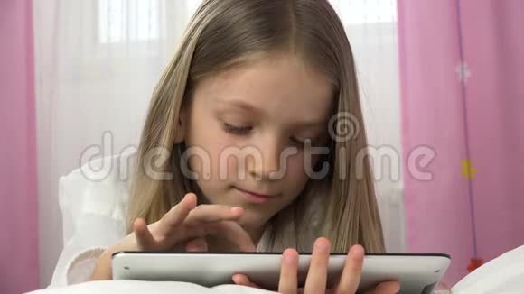 4K孩子在卧室里玩平板电脑女孩在床上放松孩子使用电脑游戏视频的预览图