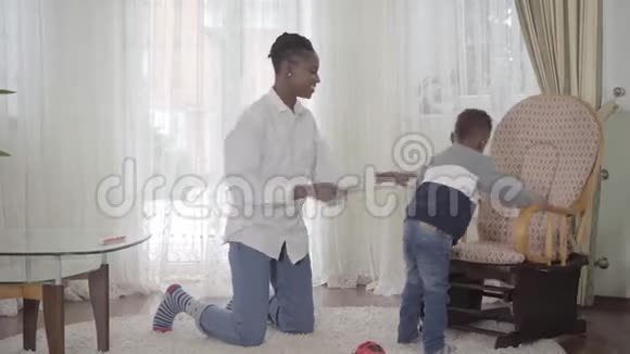 美国黑人妈妈和她可爱的小男孩一起在舒适的客厅里玩小舞蹈视频的预览图