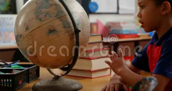 非裔美国小学生4k教室课桌学习地球仪的侧视图视频的预览图