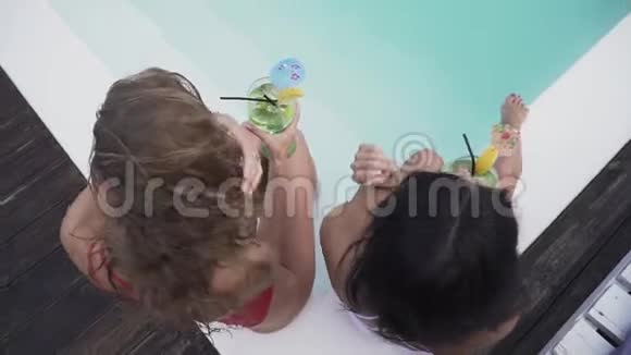 两个苗条漂亮的女孩喝着鸡尾酒在休息室里玩得很开心两个女朋友穿着泳衣视频的预览图