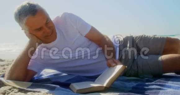 活跃的高加索人在海滩上看书的正面景色视频的预览图