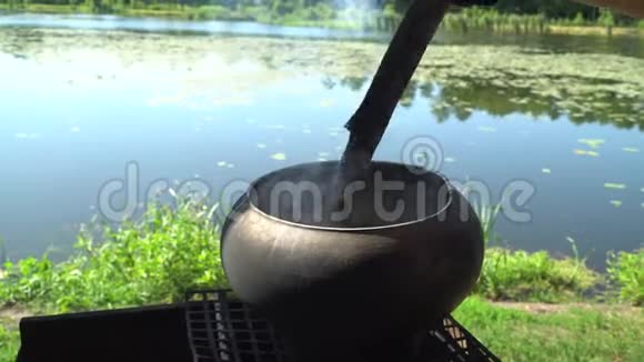 在湖底的原木大火上铁铸的大锅沸腾的耳朵视频的预览图