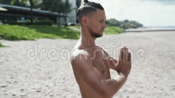 特写慢动作稳定镜头运动员双手合拢在沙滩上做瑜伽双眼紧闭视频的预览图