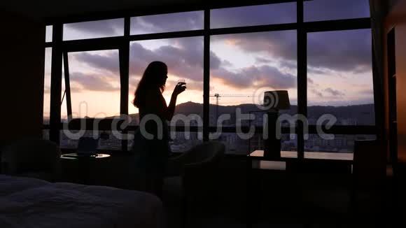 女人从窗户欣赏日落喝水巴塞罗那视频的预览图