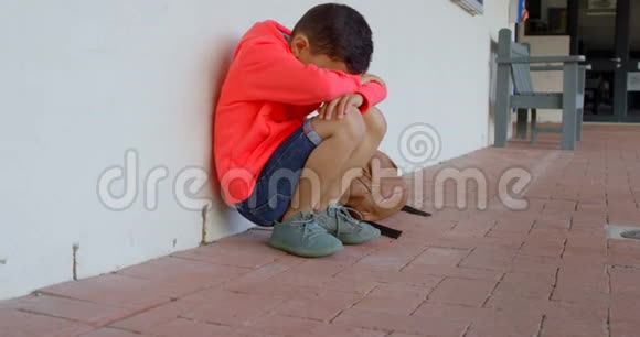 亚洲小学生的侧视头朝下独自坐在学校走廊的地板上视频的预览图