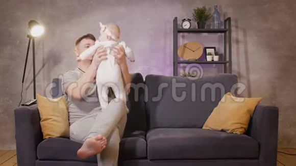 一个男人在舒适的公寓里和他的孩子在沙发上玩耍爸爸和宝宝很开心视频的预览图