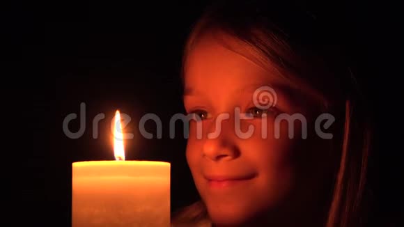 烛光下快乐的孩子夜晚微笑的祈祷孩子女孩肖像黑暗的脸视频的预览图