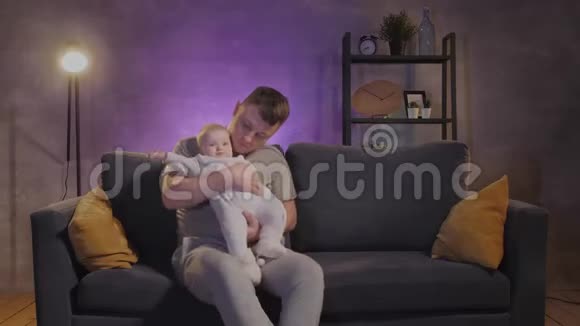 一个男人在舒适的公寓里和他的孩子在沙发上玩耍爸爸和宝宝很开心视频的预览图