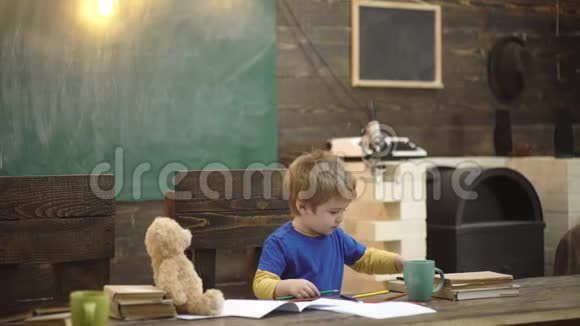 专心致志的孩子写书稿坐在书桌前的学龄前男孩在幼儿园学习书信孩子在画画视频的预览图