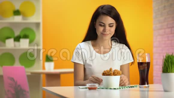 微笑的女人拿着一次性碗和脆炸鸡享受气味视频的预览图
