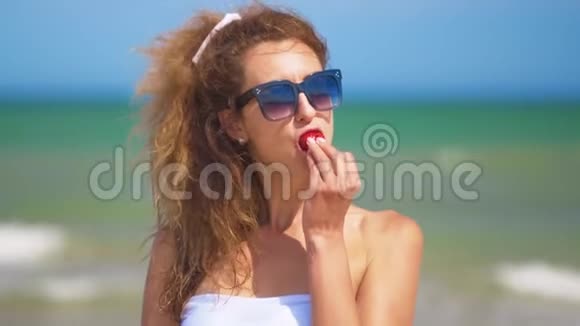 阳光明媚的夏天女人在海边吃草莓视频的预览图