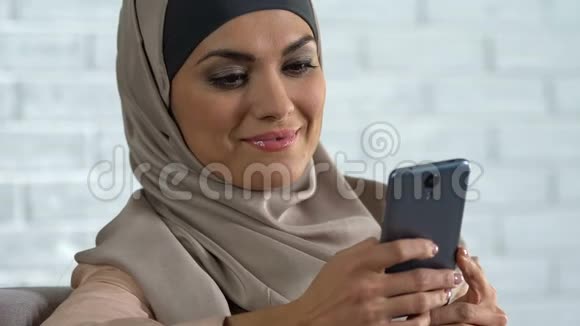 迷人的阿拉伯女人在智能手机上滚动社交网络现代科技视频的预览图