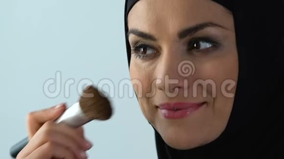 面带微笑的30多岁穆斯林妇女涂腮红抗衰老化妆品化妆视频的预览图