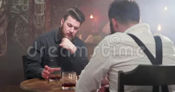 两个年轻的嬉皮士在酒吧里的一场国际象棋比赛中碰杯威士忌喝酒视频的预览图