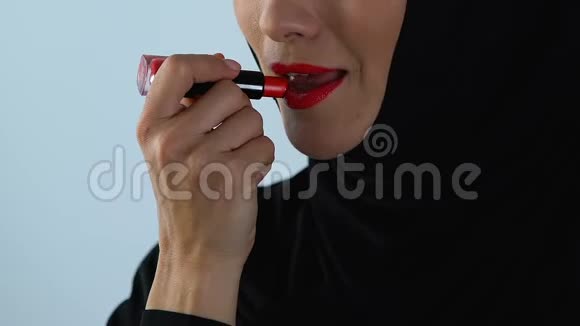 阿拉伯女性在头巾上做鲜艳的化妆涂红唇膏美容理念视频的预览图