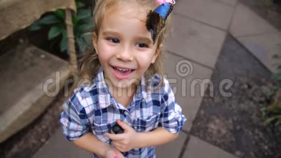 女孩很高兴也很微笑因为一只美丽的蝴蝶落在她的头上4K慢慢视频的预览图
