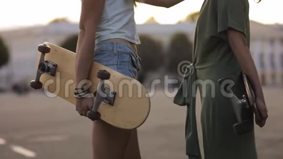 天鹤射击两位少女朋友在阳光下玩滑板在欧洲街镇大笑的肖像视频的预览图