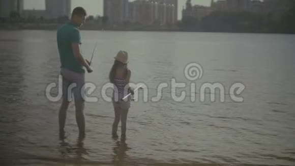 可爱的父亲和可爱的女儿在河边钓鱼视频的预览图