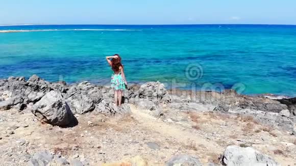 美丽的女人站在海边看着蓝色的海浪克里特岛视频的预览图