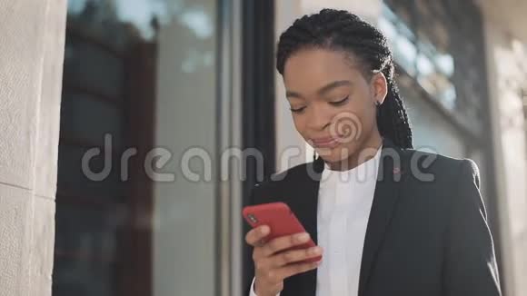 时尚的非洲女商人在户外与手机助理通话时用手机发送音频语音信息商务视频的预览图