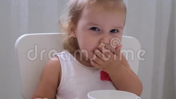 婴儿女孩在白色背景的小儿童桌上吃婴儿食品儿童的营养和喂养视频的预览图