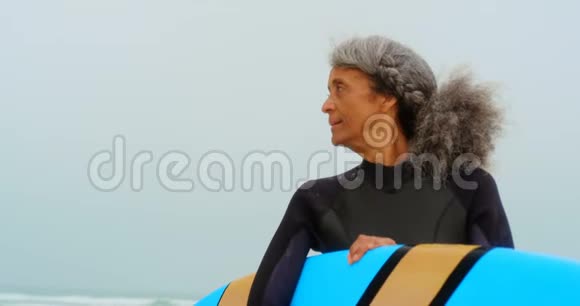 积极的非裔美国女性冲浪者站在海滩上冲浪板的正面景色视频的预览图