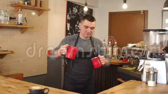 一个男人在一家现代化的咖啡店里准备卡布奇诺一个人把牛奶倒在咖啡里视频的预览图