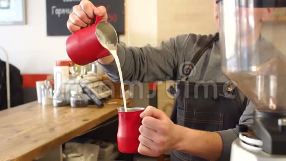 男咖啡师的特写镜头将牛奶倒入杯中准备拿铁视频的预览图