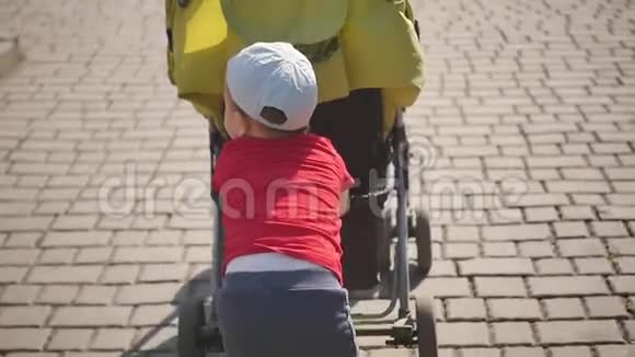 快乐的小男孩正在滚动他的婴儿车慢动作视频的预览图