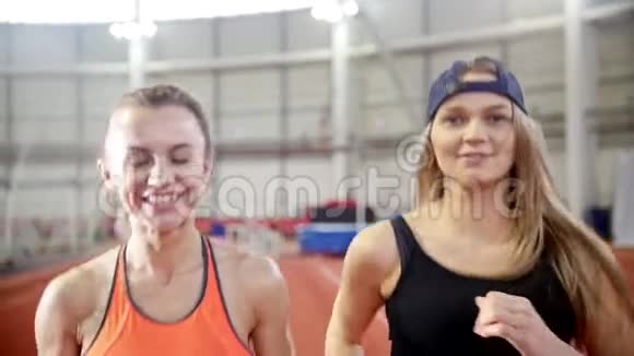 两个微笑的运动女朋友跑在跑道上视频的预览图