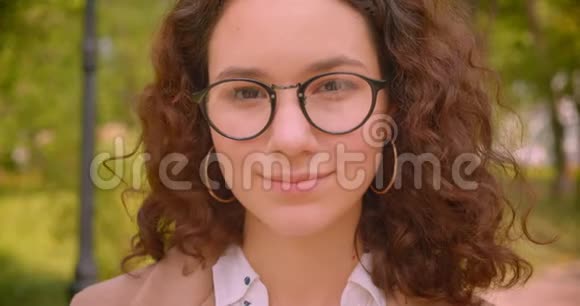 戴着眼镜的白种人年轻的长毛卷曲女学生的特写照片她开心地笑着看着镜头视频的预览图
