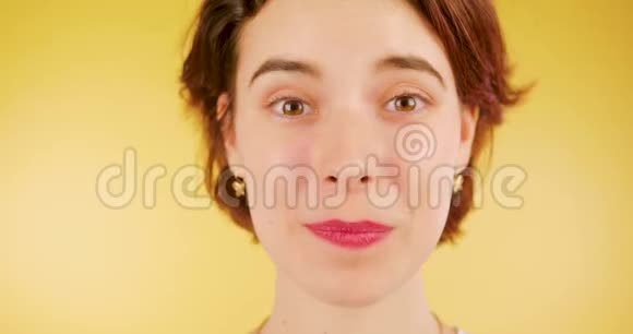 一个黑发女孩看着相机送了一个吻害羞可爱黄色背景视频的预览图