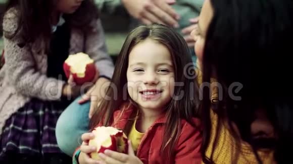 一个小女孩和家人在秋天的大自然里野餐吃苹果视频的预览图