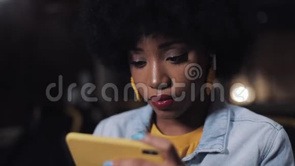 严肃的非洲裔美国妇女握着扶手在公共交通工具上看智能手机上的视频夜晚视频的预览图