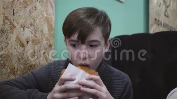 在餐馆吃汉堡的男孩这个男孩拿着一个牛肉汉堡视频的预览图