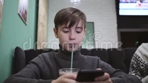 小男孩坐在咖啡馆里用吸管喝着杯子里的橙汁视频的预览图