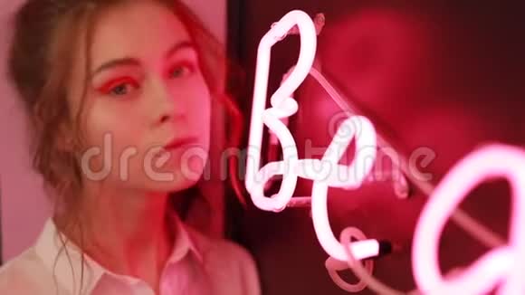 红色霓虹灯墙附近美丽女孩的创意画像视频的预览图