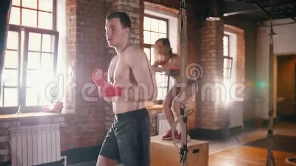 在健身房训练的运动员一个女人在盒子上跳而一个男人在打拳袋视频的预览图