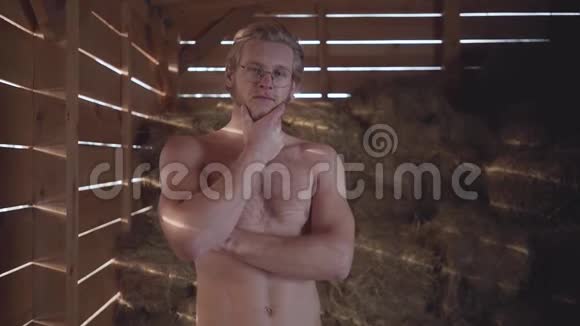 肖像吸引人的胡须男戴眼镜赤裸的躯干站在谷仓的干草背景那个家伙视频的预览图