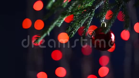 一个亮闪闪的球在一棵圣诞树的毛茸茸的树枝上背景波克灯的花环准备好的圣诞黑暗视频的预览图