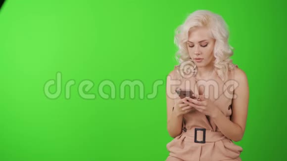 快乐的年轻女人在智能手机上聊天一个女人在绿色的背景下看镜头视频的预览图