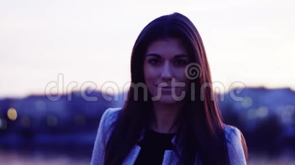 黄昏时分年轻女子站在城市的河边笑着视频的预览图